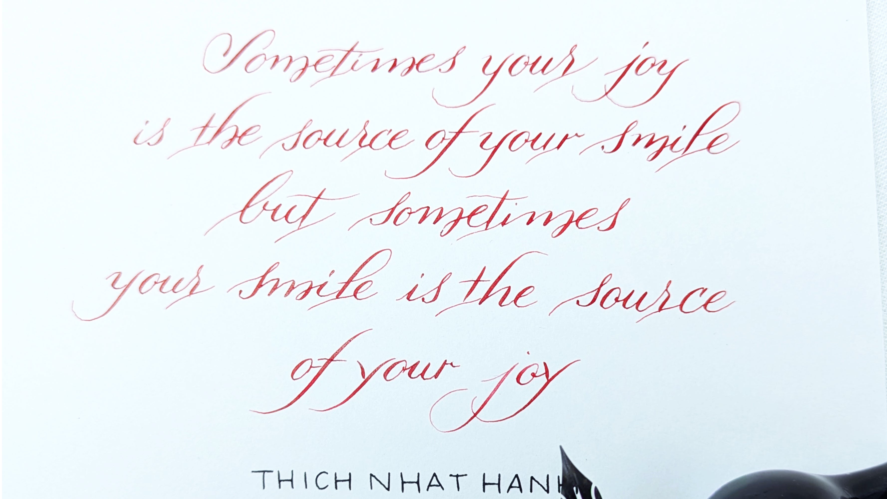 Hand written calligraphy hand in modern copperplate - Motivational quote by Thich Nhat Hanh on a white background with red text.