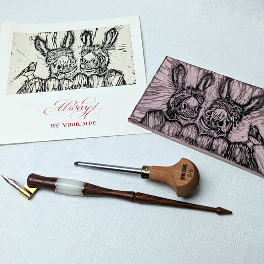 Wooden pen with ink cartridge on a white surface with two greeting cards featuring animal illustrations.