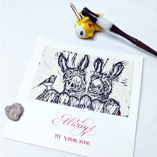This handmade card celebrates steadfast companionship with a touch of gentle humour. The lino print illustration is hand-carved and printed, capturing two donkeys standing close — unshowy, solid, and quietly devoted — with a small bird keeping watch. It’s a nod to relationships built on presence rather than performance.

The text beneath the image is written individually with a dip pen, and can be customised to suit the occasion, whether heartfelt, understated, or lightly playful.