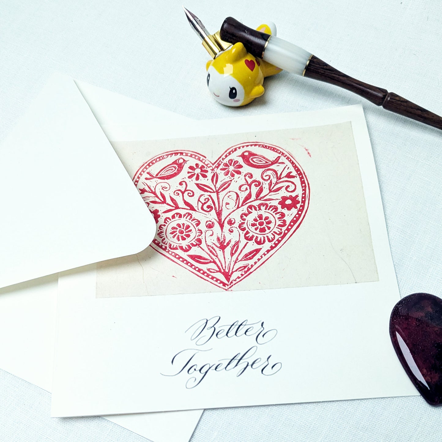 Card with red heart design and 'Better Together' text, surrounded by stationery items on a white background.
