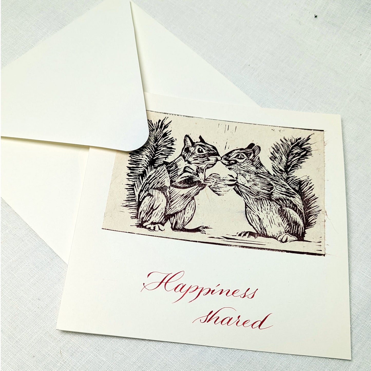 This handmade card features an original lino print of two squirrels leaning in close, caught in a moment that’s equal parts tenderness and cheek. It’s a light-hearted celebration of companionship, mutual joy, and the small, shared moments that make life brighter.

Each print is hand-pulled from a hand-carved lino block, giving the image depth, texture, and subtle variation. The accompanying text is written individually with a traditional dip pen and can be customised to suit your occasion.