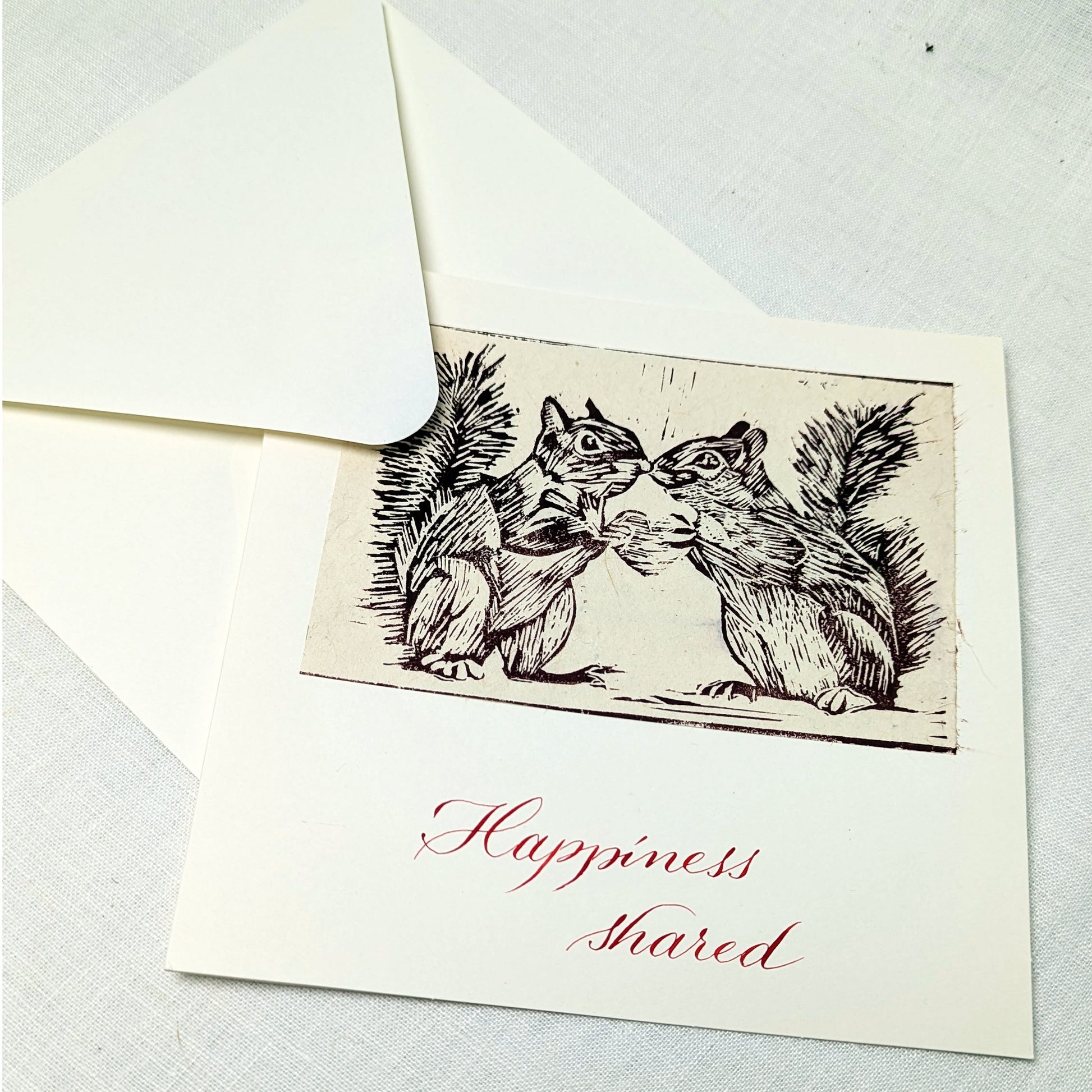 This handmade card features an original lino print of two squirrels leaning in close, caught in a moment that’s equal parts tenderness and cheek. It’s a light-hearted celebration of companionship, mutual joy, and the small, shared moments that make life brighter.

Each print is hand-pulled from a hand-carved lino block, giving the image depth, texture, and subtle variation. The accompanying text is written individually with a traditional dip pen and can be customised to suit your occasion.