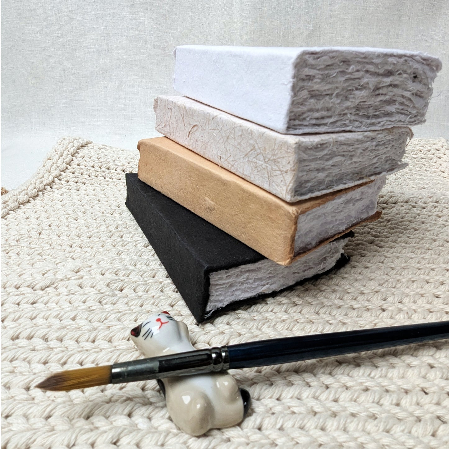 Stack of books with a brush holder and paintbrush on a textured surface