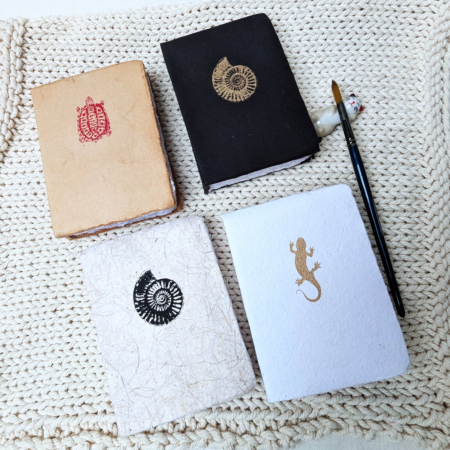 Four notebooks with embossed designs on a textured surface
