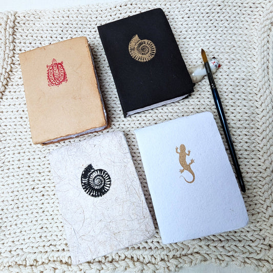 Four notebooks with embossed designs on a textured surface