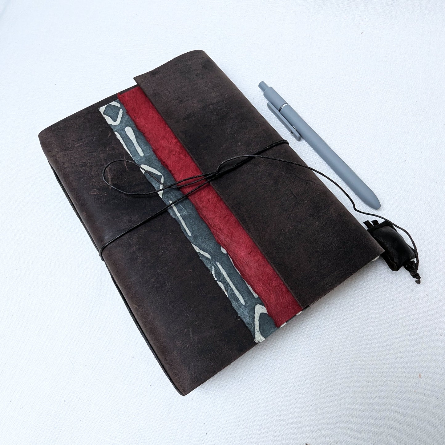 Black notebook with red and gray design, pen, and charger on a white background