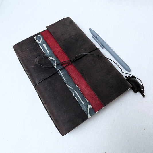 Black notebook with red and gray design, pen, and charger on a white background