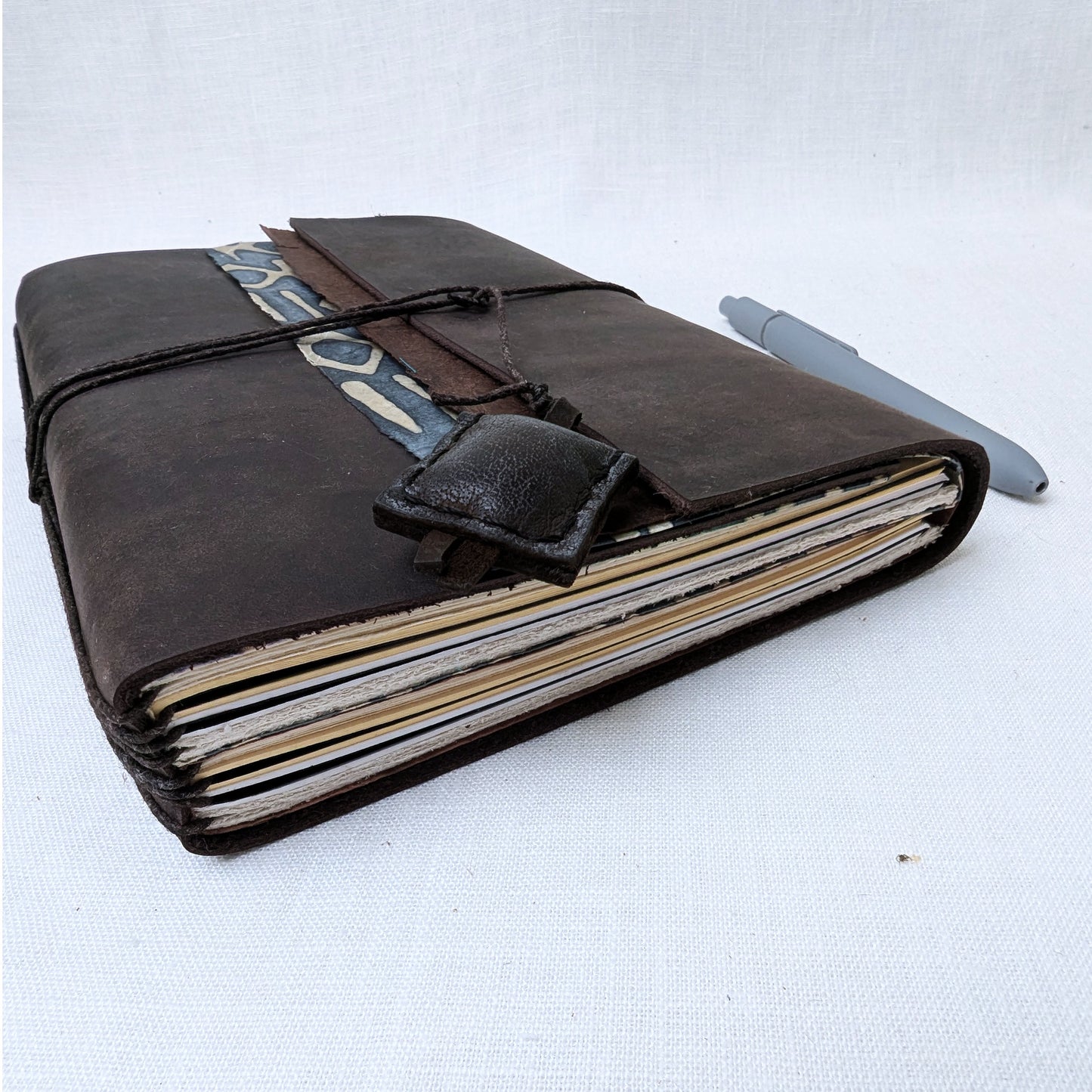 Brown leather-bound notebook with a pen on a white background
