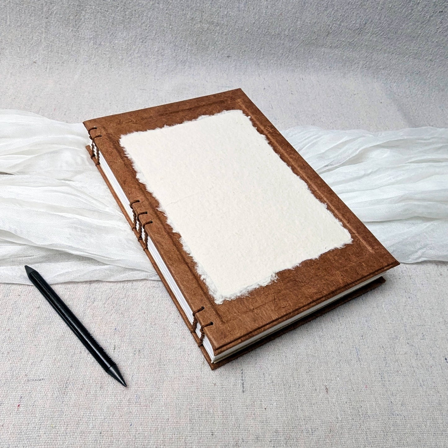 Rust drawing notebook with white pages on a textured surface