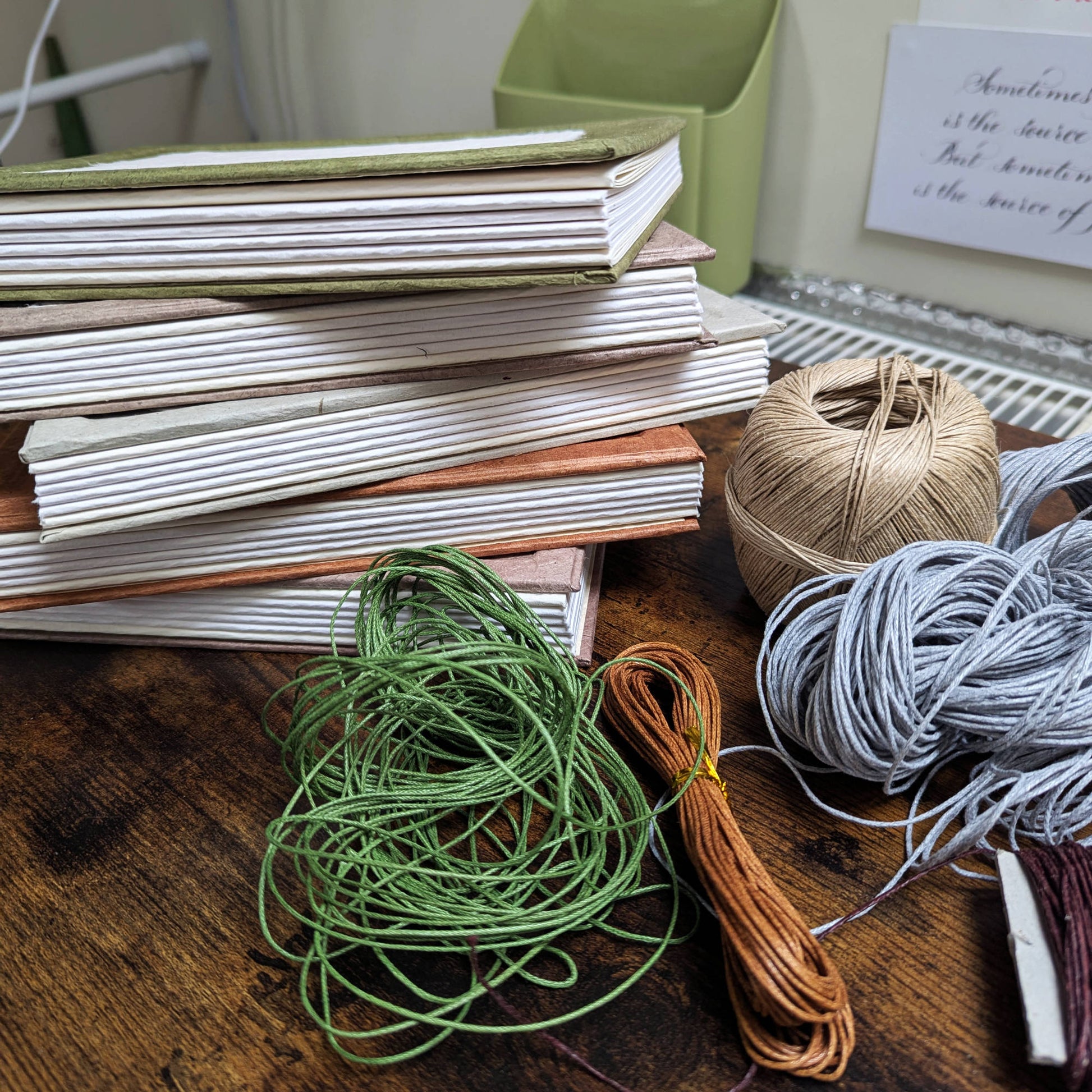Artisanal stack of books  being handsewn in leitrim, Ireland, using  spools of thread on a wooden surface